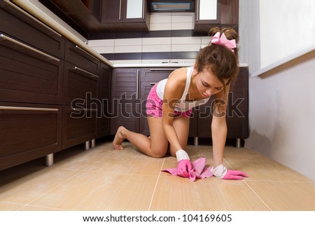 Young woman cleaning the kitchen floor at home