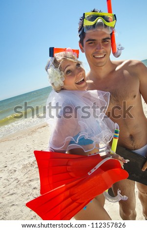 Romantic newly-married couple having fun on the beach, wearing mask and fins
