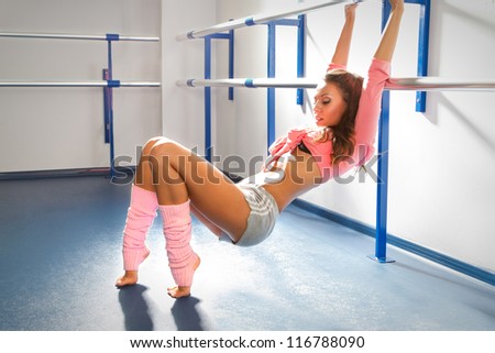 Ballet dancer relaxing after exercise by bar in dance studio