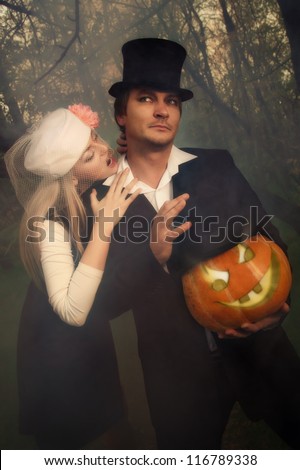 Portrait of a beautiful  vampire couple in medieval costumes with Halloween pumpkin in forest