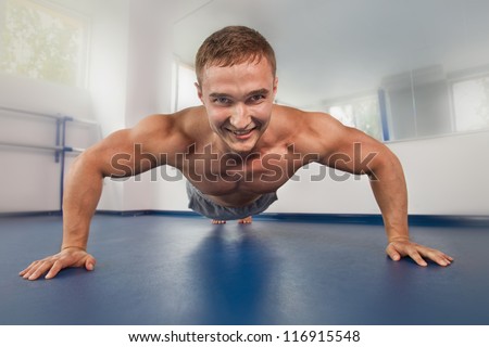 Muscular young bodybuilder pushing up on floor