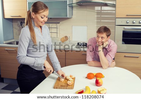 Young woman cutting fruits with her boyfriend on kitchen