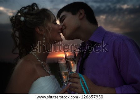 Portrait of bride and groom making a toast at sunset in the field outdoors