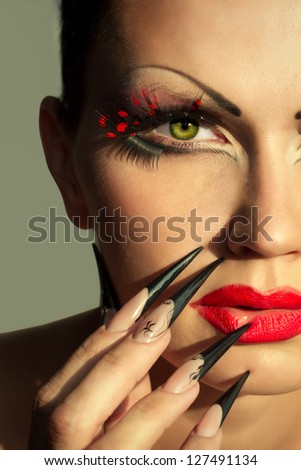 Woman face with creative fashion makeup and manicure in the sunlight