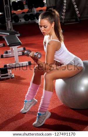 Woman Lifting Weights on Pilates ball workout posture in fitness club