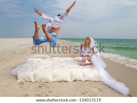 Happy Groom flying on bed to his bride on the beach