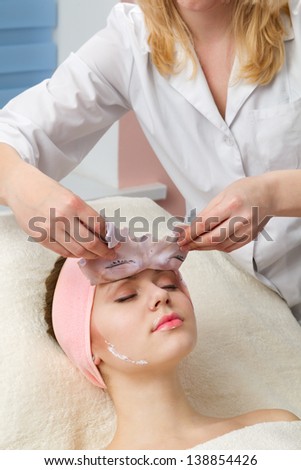 Young beautiful girl receiving facial mask in spa beauty salon
