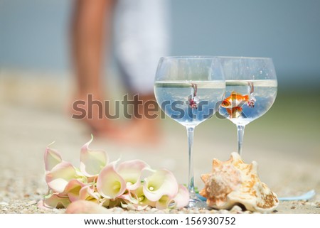 Reflection of holding bride and groom in wine glasses with golden fishes