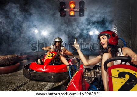 girl is driving Go-kart with speed in Karting. Aggressive woman indicating finger
