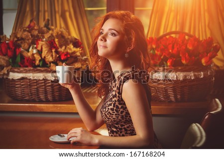 Woman with an aromatic coffee in hands at home next to window