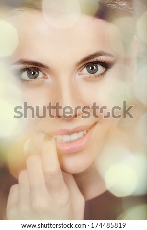 Portrait of beautiful young smiling woman. View through illuminated bokeh circles.