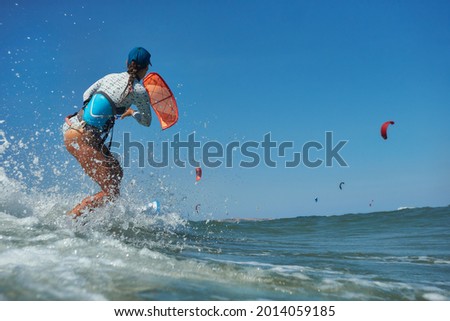 Similar – Image, Stock Photo Female kite surfer riding on board in sea