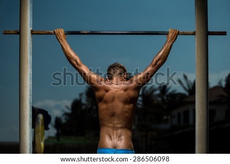 Closeup of young strong athlete doing pull-up on horizontal bar