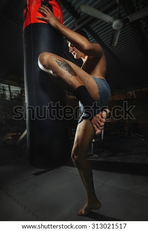 Fighter Practicing Some Kicks With Punching Bag - A Man With A Tattoo Boxing On dark Background