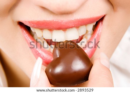 Beautiful girl eating chocolate candy close-up
