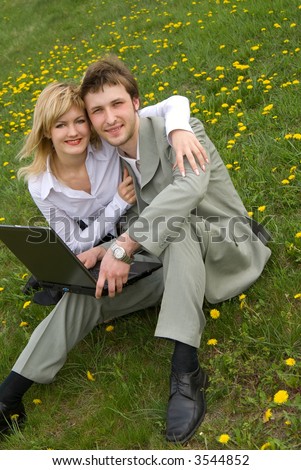 Young cheerful couple working on laptop at outdoor environment