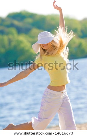 HAppy young model jumping on river beach