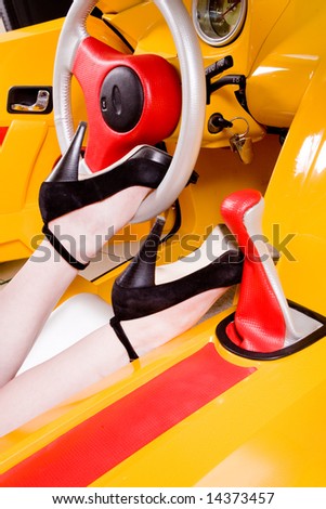 Pretty woman legs on the stirring wheel of racing car