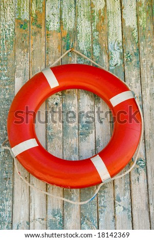 Red life buoy on wooden wall background