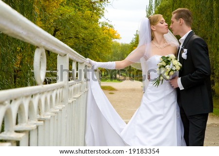 Colorful wedding shot of bride and groom standing on the bridge