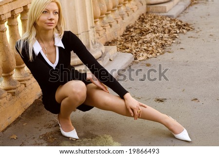 Sweet fashionable girl sitting near roman-style column