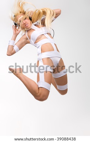 Excited blond model in futuristic style clothes with headphones jumping