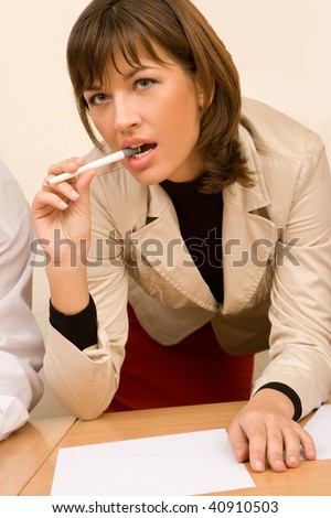 Beautiful businesswoman at office, thoughtfully biting pen