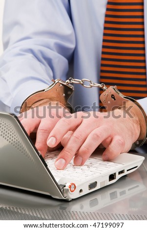 Businessman\'s hands bound to laptop with handcuffs