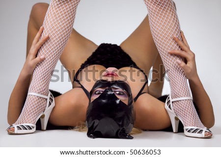 Hot beautiful model in latex black cat costume between legs of her dominatrix
