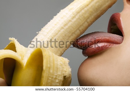 Close-up female mouth licking peeled banana