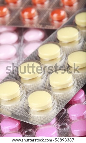 Stack of packs of pink yellow and red pills, abstract medical background