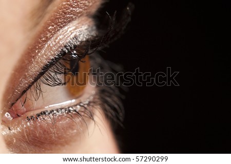 Close up of beautiful woman`s open brown eye peeping in darkness