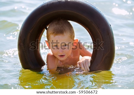 The boy in a rubber ring in shining water