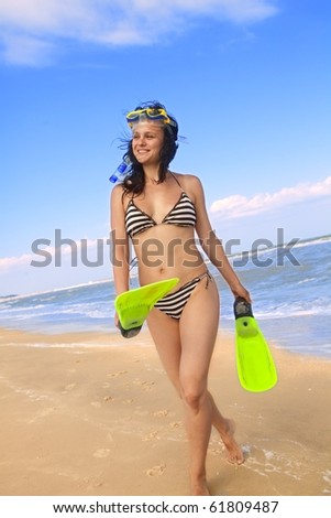 Portrait of smiling girl in swimming mask and fins against the sea and sky