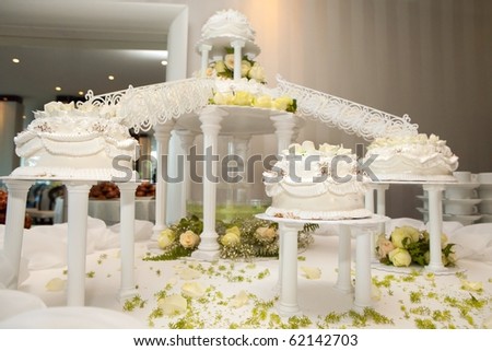 Wedding cakes with roses connected by bridges on the decorated table