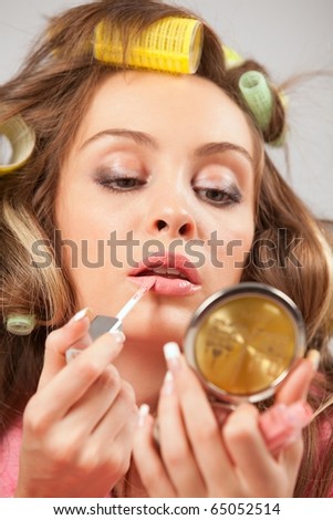 Portrait of beautiful woman in pink bath robe applying liquid glossy lipstick , on white background