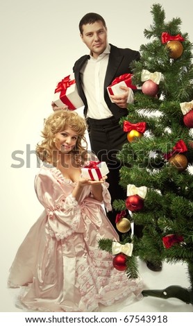 Victorian couple stand  near a Christmas tree with gift boxes. Isolated over white background