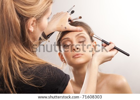 Backstage scene: Professional Make-up artist doing glamour model makeup at work