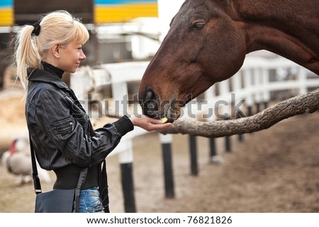 Beautiful girl feeding  her horse at ranch