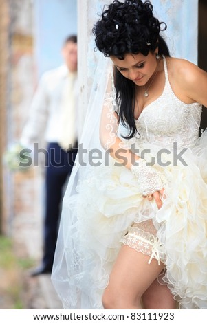 A bride putting on her wedding garter against old grunge place