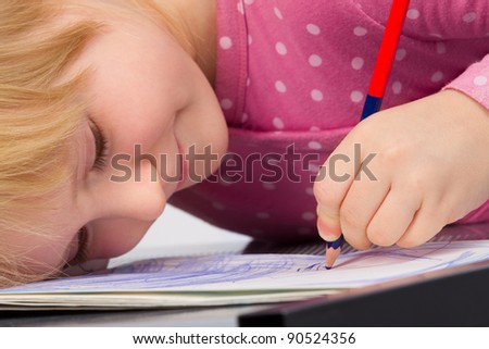 Portrait of cute little girl is drawing with pencil