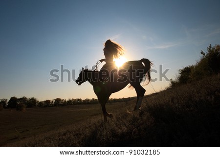 Beautiful girl  riding a horse against sun