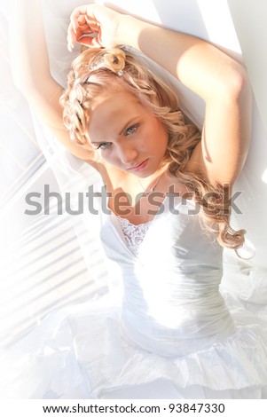 Beautiful young  bride wearied in dress and veil sitting on the floor.