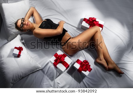 Portrait of sexy beautiful woman with gifts on bed
