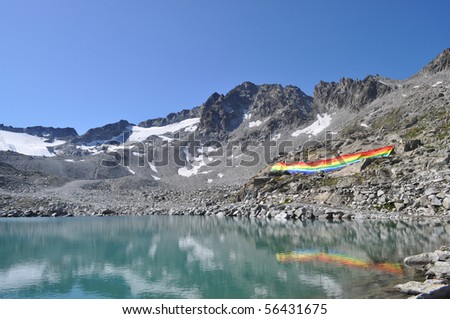 Peace flag dropped in mountain reflected in a lake, Adamello Italy