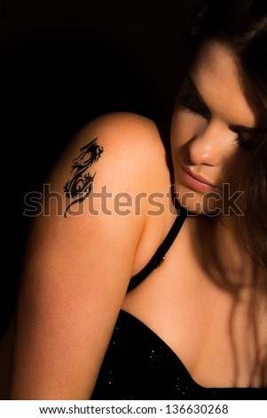 Young sexy women with tribal dragon tattoo on her shoulder
