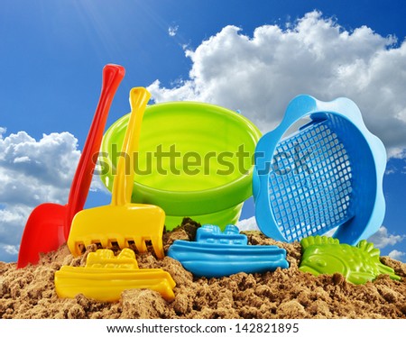 Plastic children toys for playing in sandpit or on a beach over the blue sky