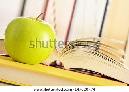 Composition with green apple and books on the table