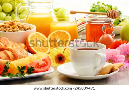 Breakfast consisting of fruits, orange juice, coffee, honey, bread and egg. Balanced diet