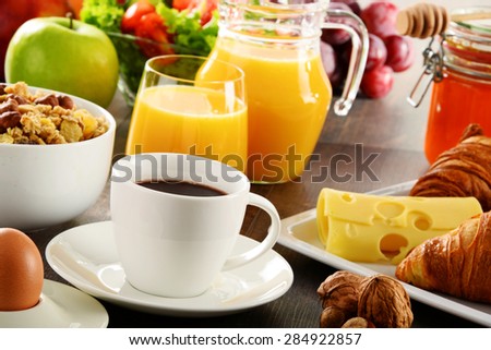 Breakfast consisting of fruits, orange juice, coffee, honey, bread and egg. Balanced diet.